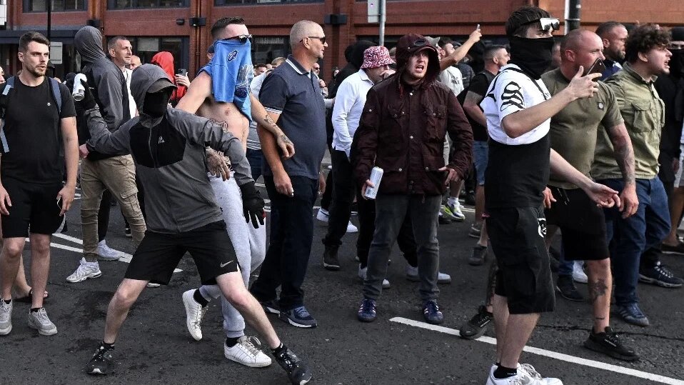 A masked protester throws a can of beer towards riot police in Bristol, southern England, on 3 August 2024 during an 'Enough is Enough' demonstration (Justin Tallis/AFP)