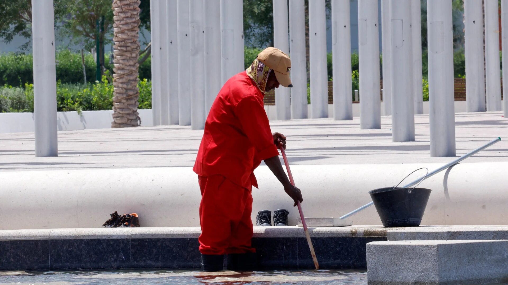 A worker cleans a water pond in Doha on 10 May 2023 (AFP/File photo)