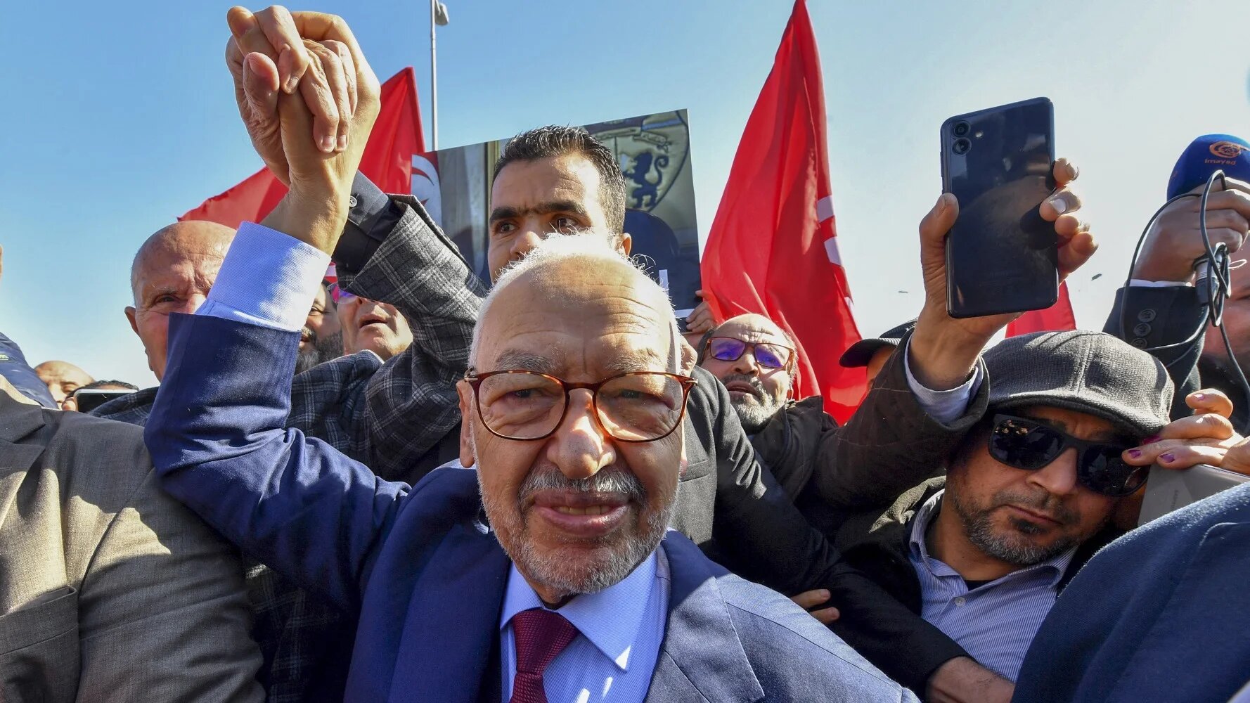 Rached Ghannouchi greets supporters upon arrival at a police station in Tunis on 21 February 2023 (Fethi Belaid/AFP)