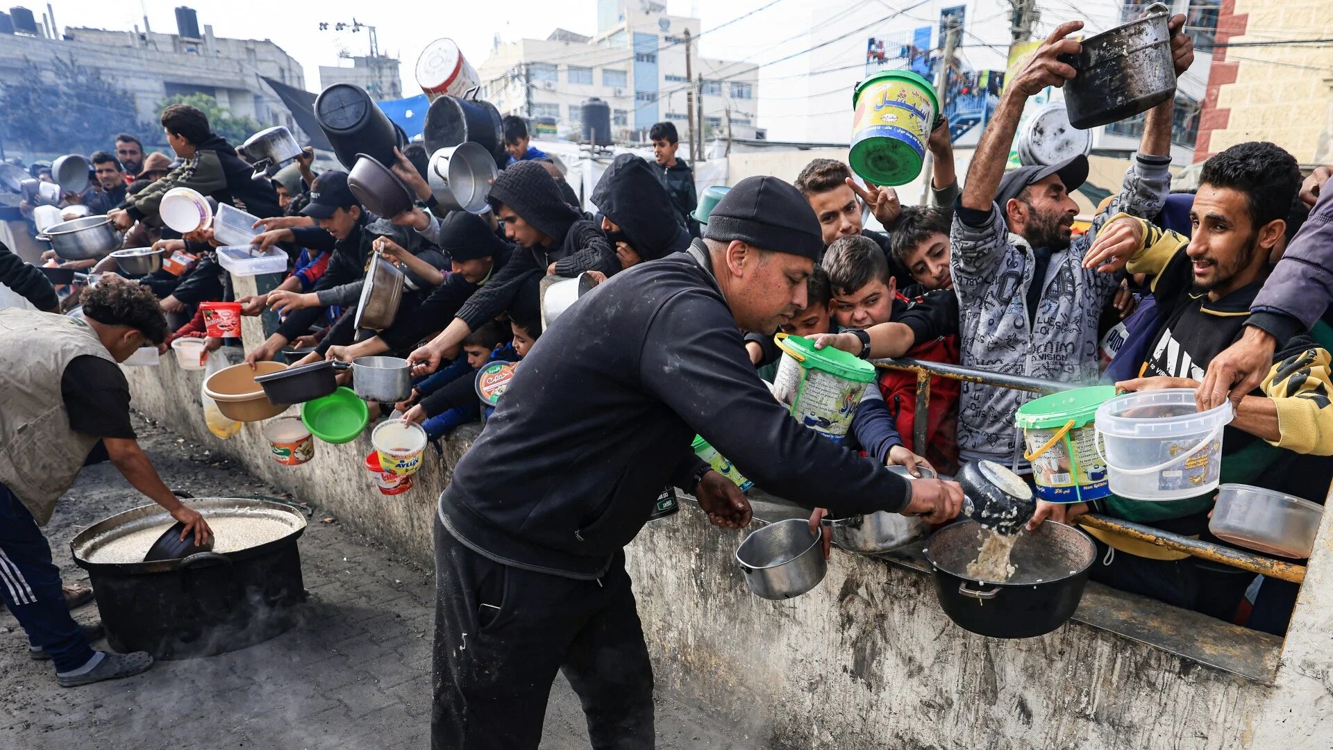 Palestinians collect food at a donation point in a refugee camp in Rafah in the southern Gaza Strip on 23 December 2023 (AFP/Mahmud Hams)