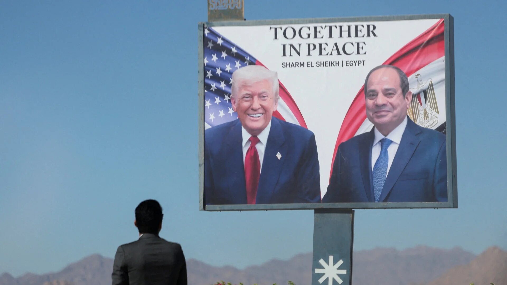 A man stands by a poster of Donald Trump and Abdel Fattah el-Sisi at Egypt's Sharm el-Sheikh, 13 October 2025 (Reuters/Mohamed Abd El Ghany)
