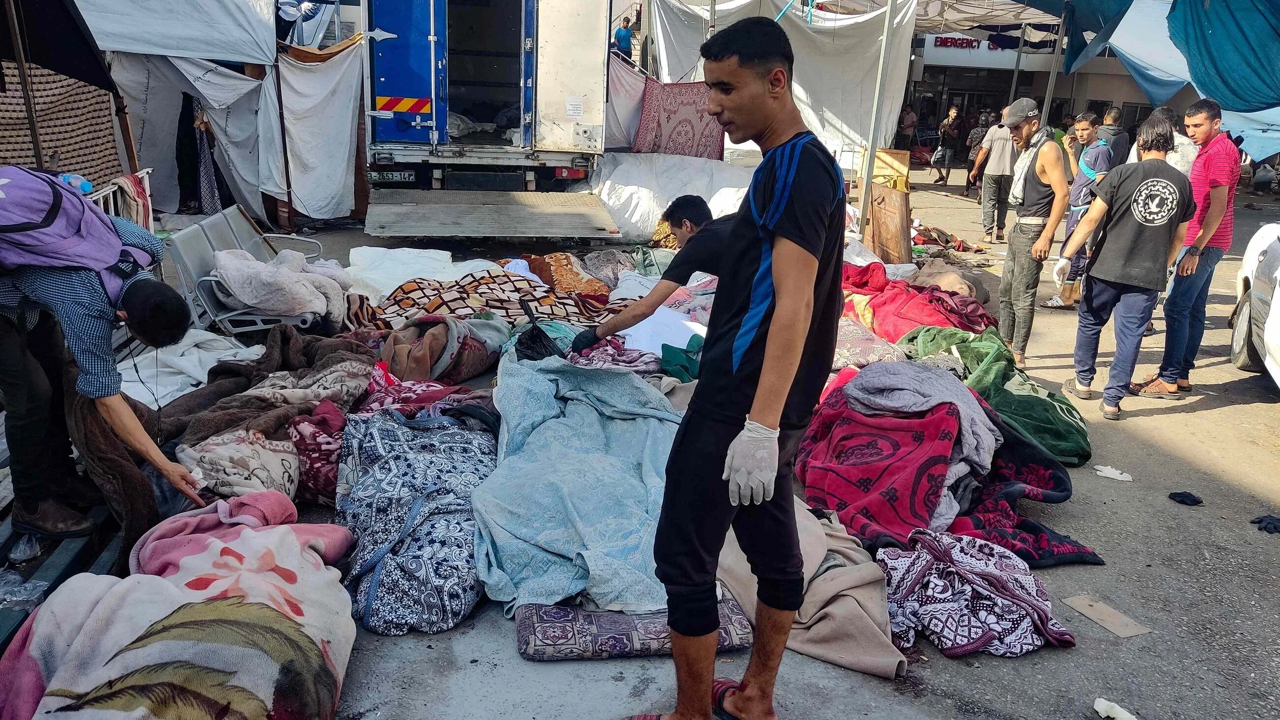 Men at al-Shifa hospital inspect bodies left outside in its courtyard on 10 November (AFP)