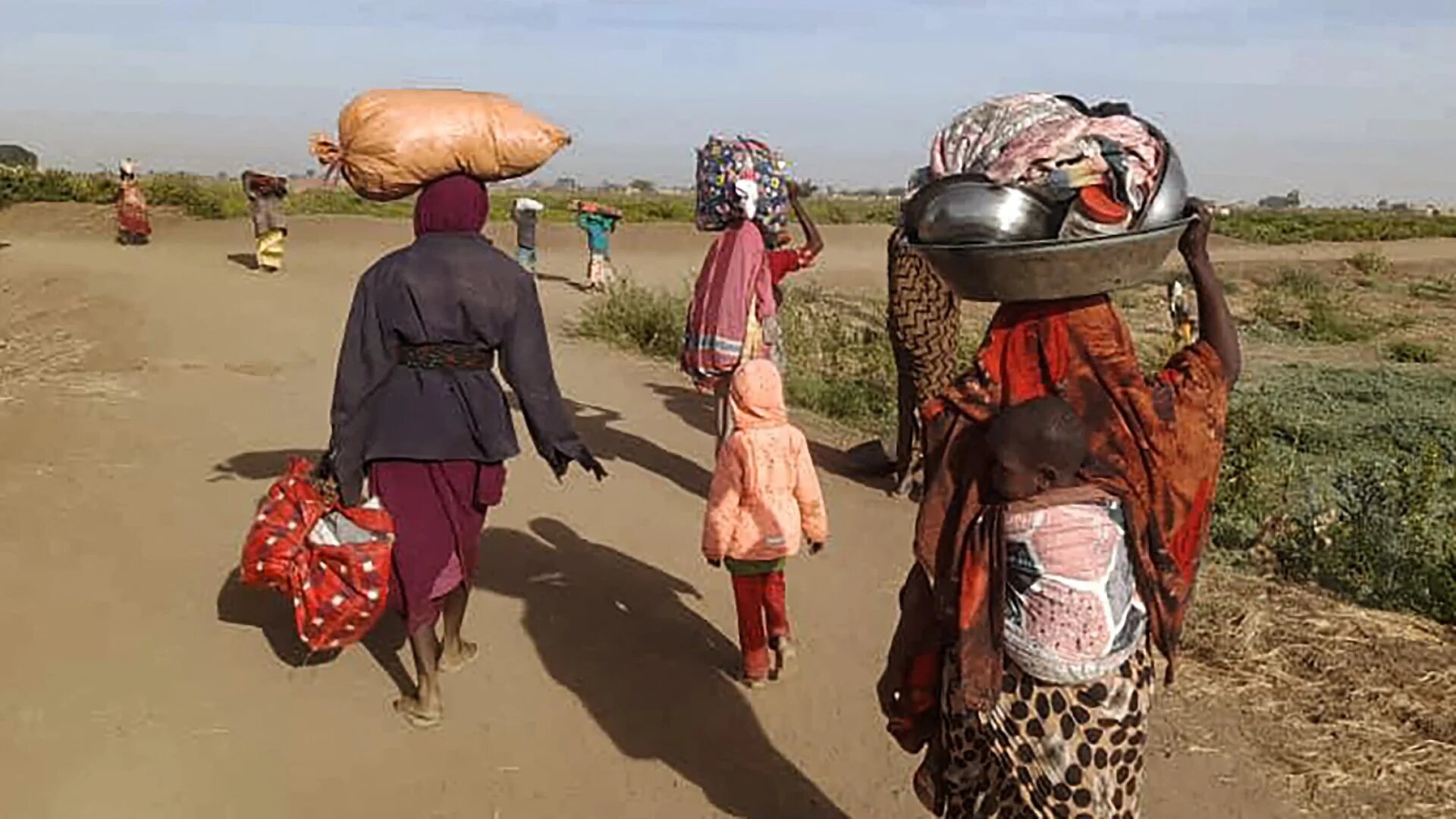 Displaced Sudanese women carry their belongings as they walk toward a camp near the town of Tawila in North Darfur on 11 February 2025 (AFP)