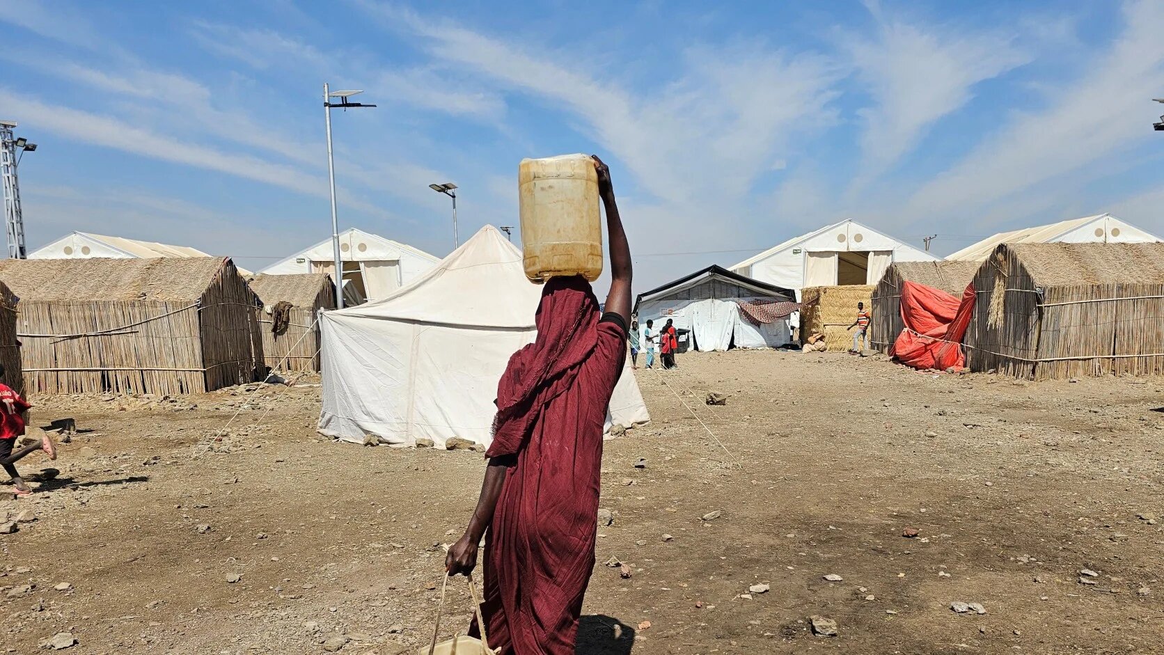 A Sudanese woman carries water at the Abu al-Naga displacement camp in Gedaref State, 420km east of the capital Khartoum on 6 February 2026 (AFP)