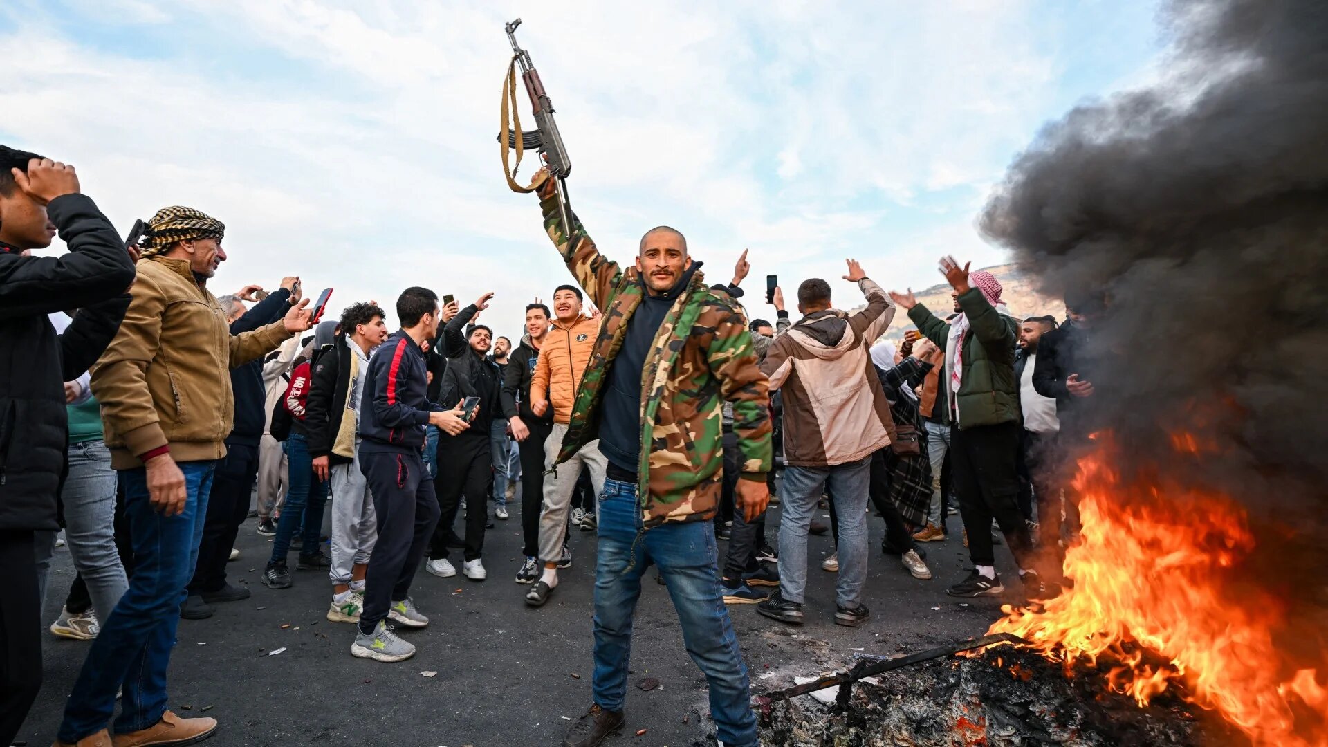 People celebrate at Umayyad Square in Damascus on 8 December (AFP/Louai Beshara)