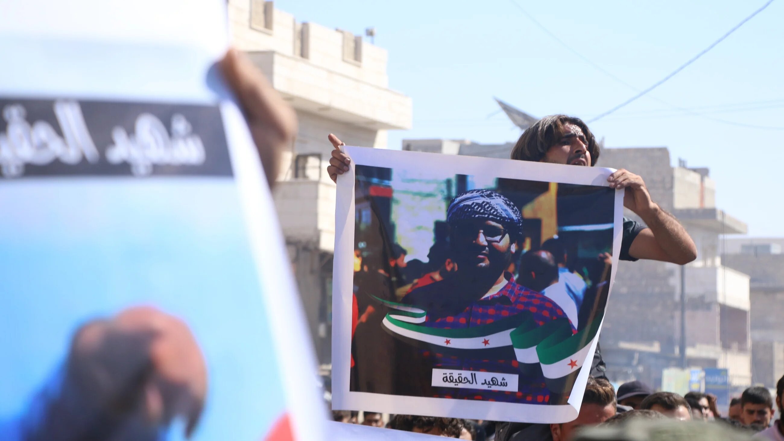 Photo of Syrian activist Muhammad Abdul Latif, who was killed by unknown assailants in al-Bab city, held by mourners during his funeral on 8 October 2022 (MEE/Walid al-Idlibi)