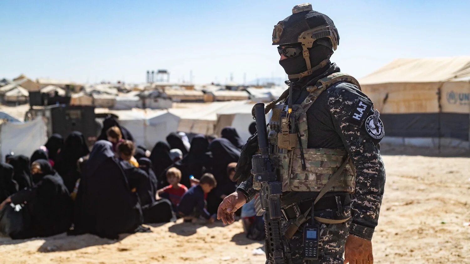 A member of the Syrian Kurdish Asayish security forces stands guard at the Kurdish-run al-Hol camp, which holds relatives of suspected Islamic State (IS) group fighters, on 28 August 2022