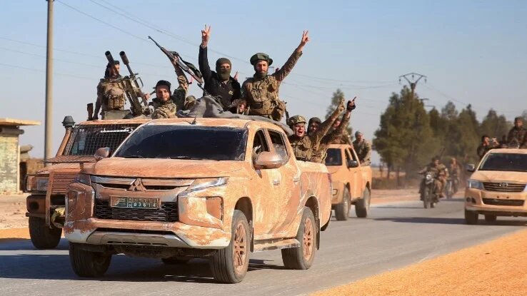 Anti-government fighters ride military vehicles in the eastern part of Syria’s Aleppo province on 1 December 2024 (Aref Tammawi/AFP)