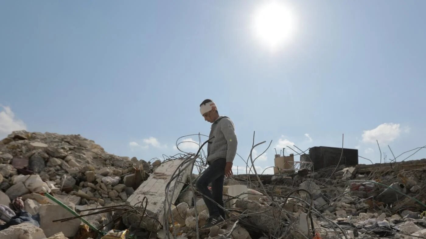 Un jeune garçon syrien qui a perdu toute sa famille à la suite des séismes marche au milieu des décombres de sa maison à Jandairis, dans la province syrienne d’Alep, le 11 février 2023 (AFP)