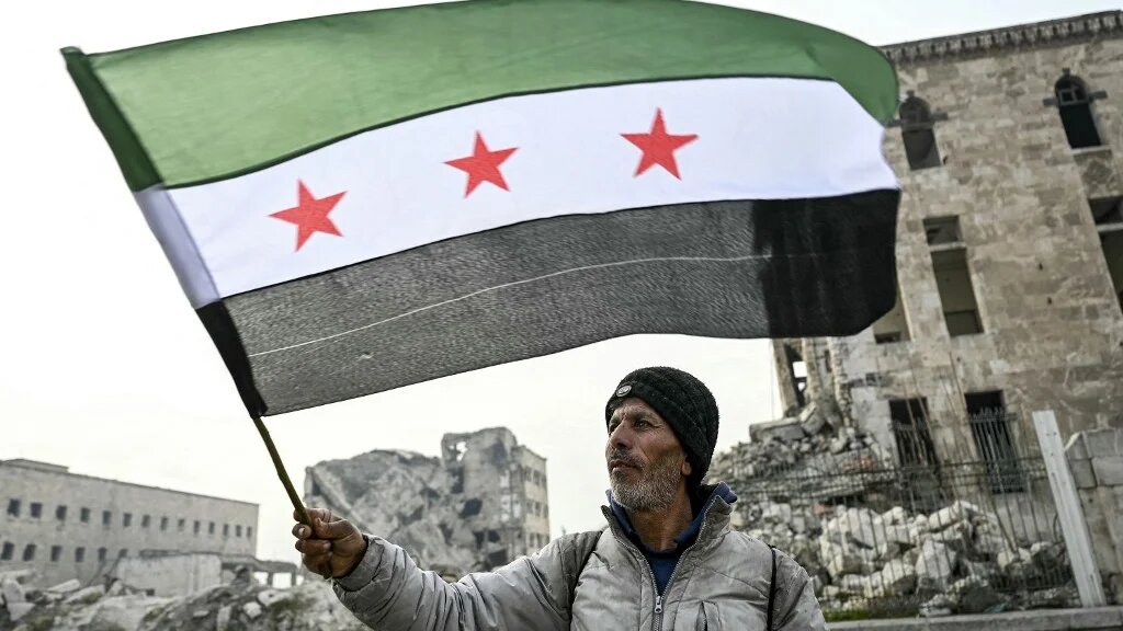 A man waves a Syrian flag in Aleppo on 11 December 2024 (Ozan Kose/AFP)