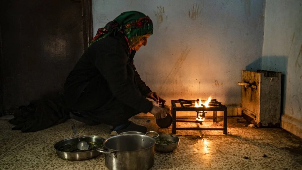 A woman cooks inside a school where displaced families are sheltering in the northeastern city of Hasakah, Syria, on 5 January 2025 (Delil Souleiman/AFP)