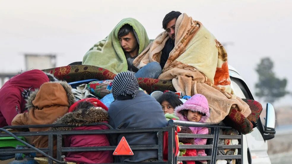 Displaced Syrian Kurds ride vehicles loaded with their belongings on the Aleppo-Raqqa highway on 2 December 2024 (Rami al-Sayed/AFP)