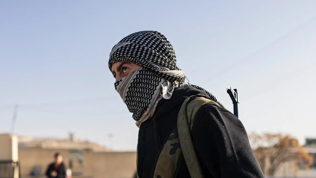 A rebel fighter patrols a military base in the capital, Damascus, on 26 December 2024 (AFP)