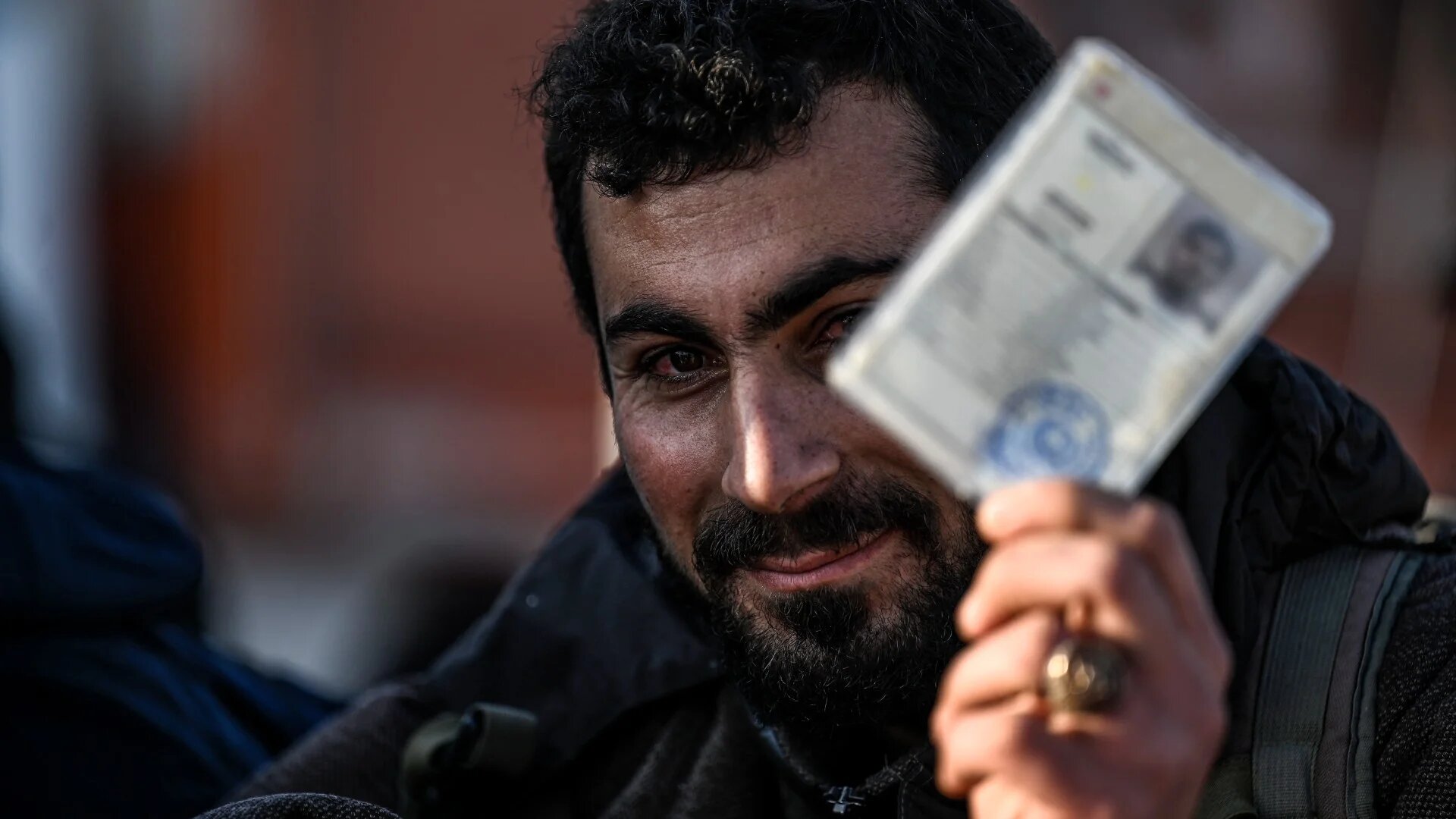 A Syrian who lives in Turkey shows his Turkish temporary ID document as he waits before entering in Syria in Hatay, on 9 December (Ozan Kose/AFP)