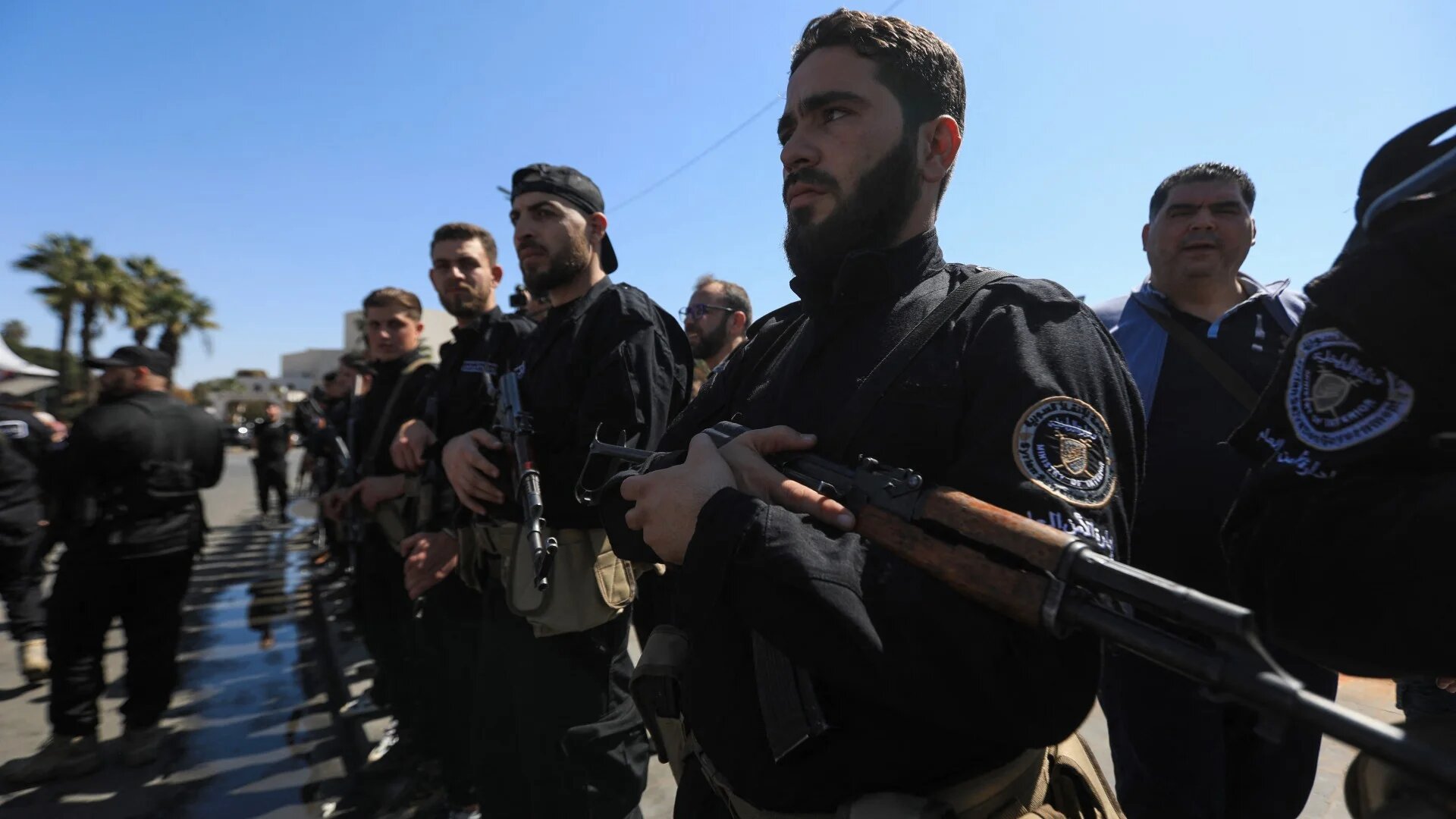 Members of Syrian security forces stand guard as people celebrate the fourteenth anniversary of Syria's uprising at a rally in Umayyad Square in Damascus on 15 March 2025 (AFP/Bakr al-Kasem)
