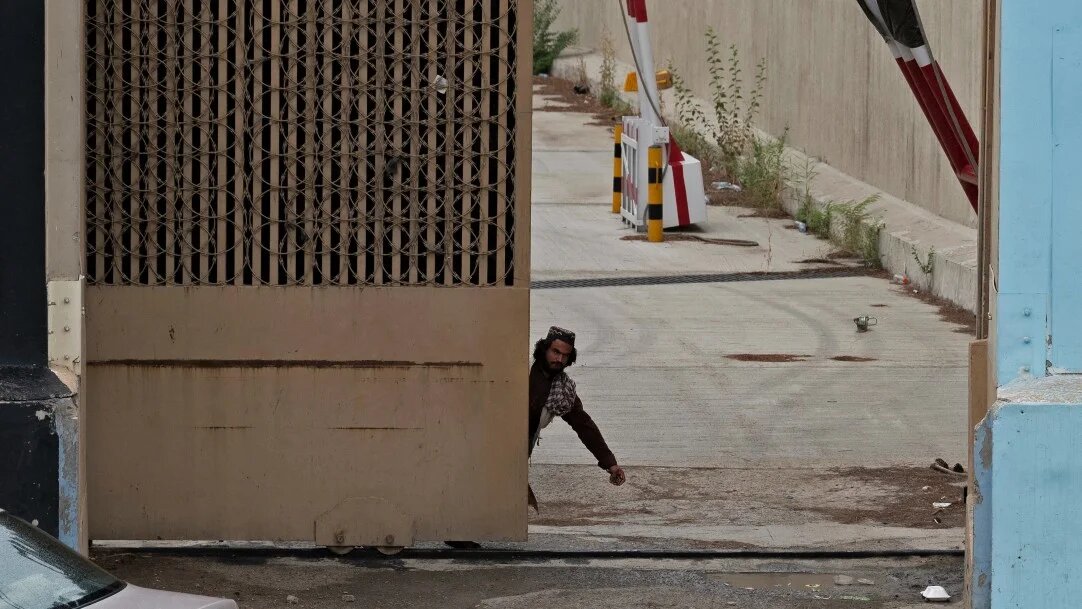 A Taliban fighter prepares to close the entrance gate of the US embassy in Kabul, on 15 August 2022.