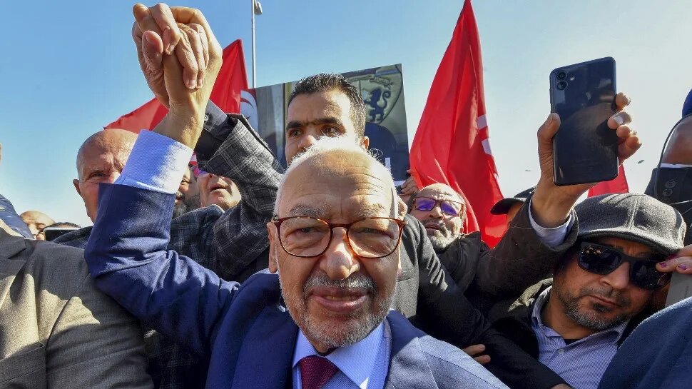Ennahdha leader Rached Ghannouchi greets supporters upon arrival to a police station in Tunis, on 21 February 2023 (Fethi Belaid/AFP)