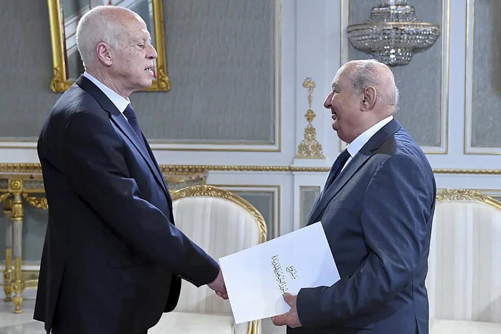 Le président de la Commission nationale consultative pour une nouvelle République, Sadok Belaïd, remet au président Kais Saied le projet de Constitution, le 20 juin 2022, à Tunis (AFP)