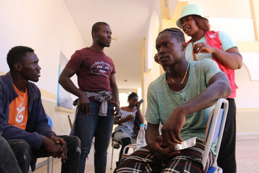Un membre du Croissant-Rouge tunisien s’adresse aux migrants qui ont fui les violences à Sfax vers la zone tampon militarisée entre la Tunisie et la Libye, le 12 juillet 2023 (AFP/Fathi Nasri)