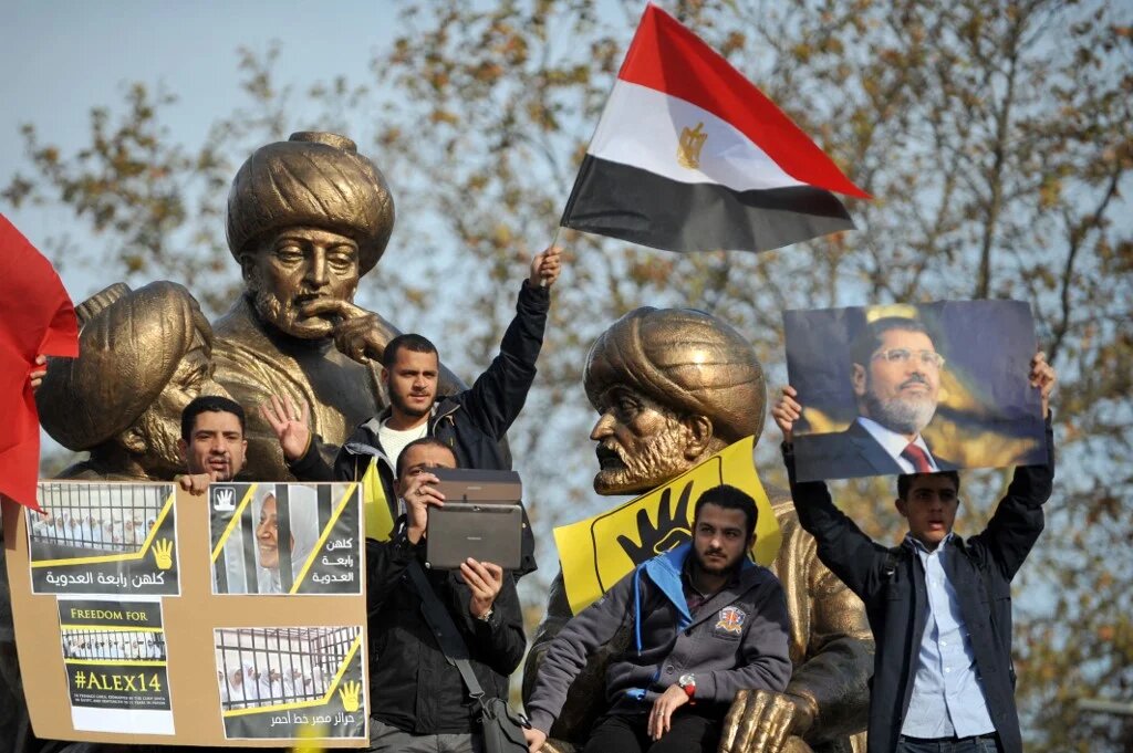 Protesters flash the four-finger sign and hold a picture of late Egyptian President Mohamed Morsi on 29 November, 2013 during a pro-Morsi rally in Istanbul (AFP)