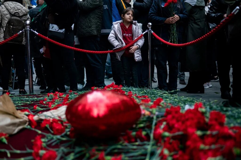 Une jeune fille regarde les gens pleurer les victimes de l’explosion du 13 novembre dans la rue commerçante animée d’Istiklal à Istanbul le 14 novembre 2022 (AFP/Yasin Akgul)