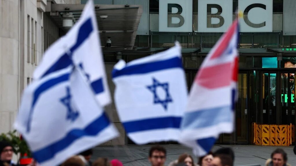 Protesters hold placards and wave Israeli flags as they take part in a demonstration outside BBC headquarters in London on 4 February 2024 (Henry Nicholls/AFP)