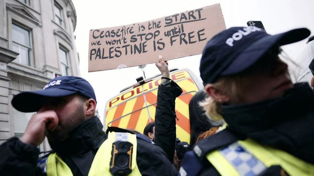A protester holds up a placard behind the police line at a demonstration for Palestine in central London, on 18 January 2025 (Benjamin Cremel/AFP)