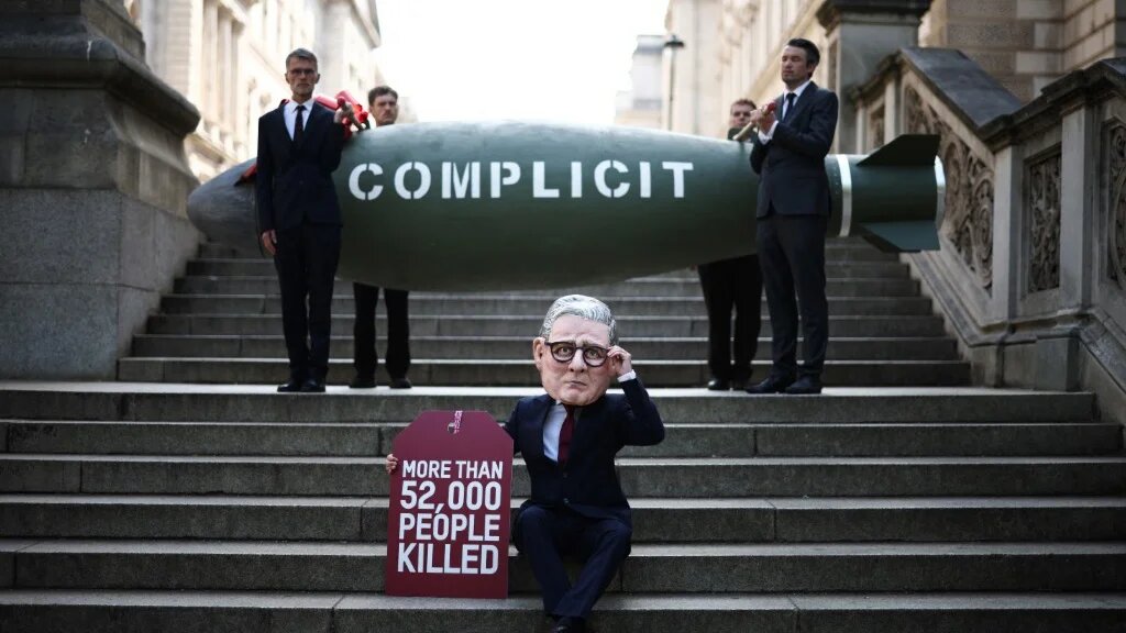 A protester dressed as British Prime Minister Keir Starmer poses by a replica bomb, and holds a sign showing the Gaza death toll, in London on 12 May 2025 (Henry Nicholls/AFP)