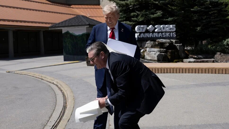 British Prime Minister Keir Starmer picks up a trade agreement dropped by US President Donald Trump during the G7 Summit in Kananaskis, Canada, on 16 June 2025 (Brendan Smialowski/AFP)