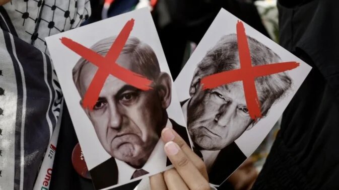 A protester holds crossed-out photos of Israeli Prime Minister Benjamin Netanyahu and US President Donald Trump by the American embassy in Jakarta on 21 March 2025 (Bay Ismoyo/AFP)