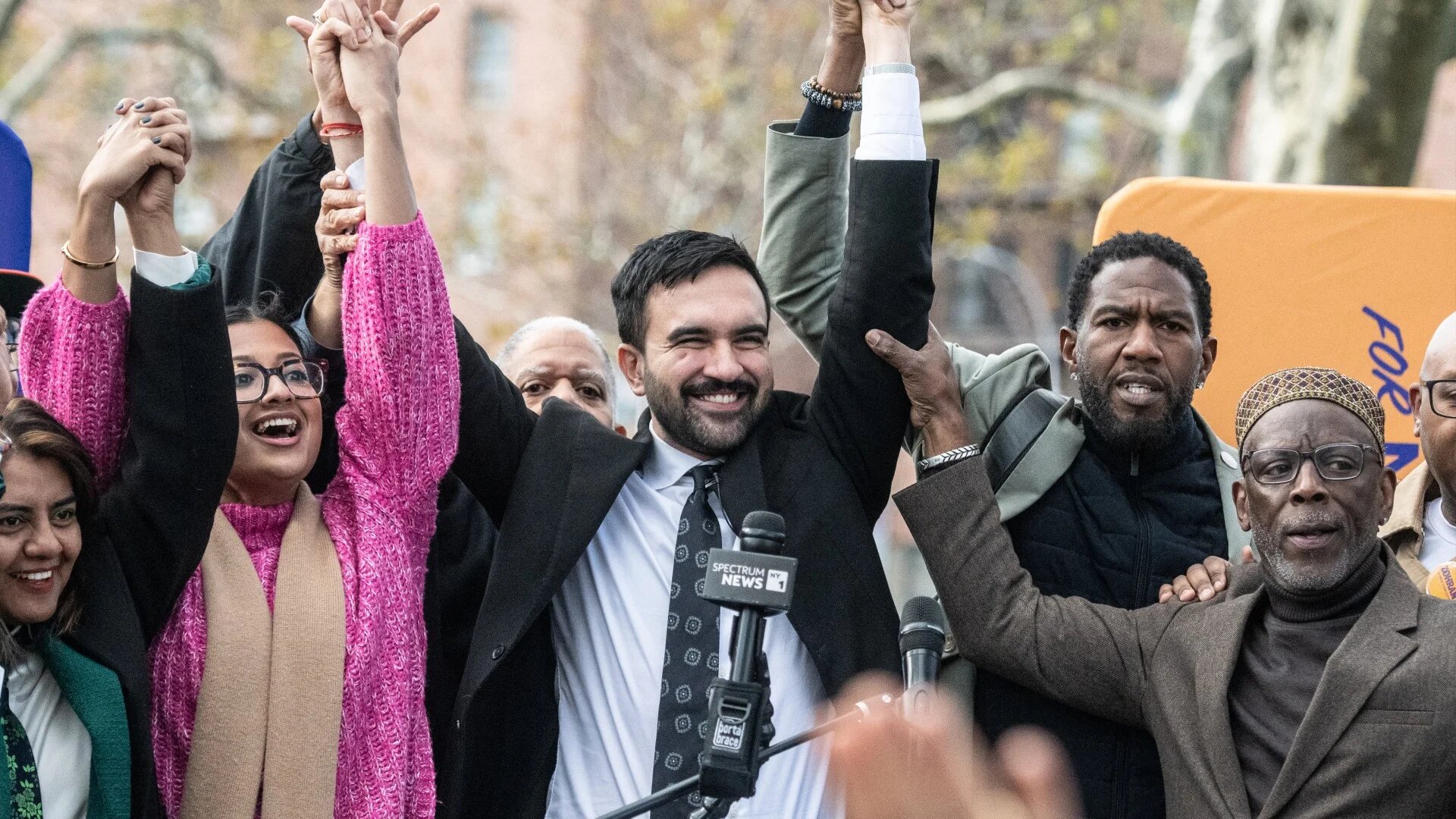 Zohran Mamdani (C) raises his hands with supporters during a campaign event in the Queens borough of New York City on 1 November 2025 (Stephanie Keith/Getty Images via AFP)