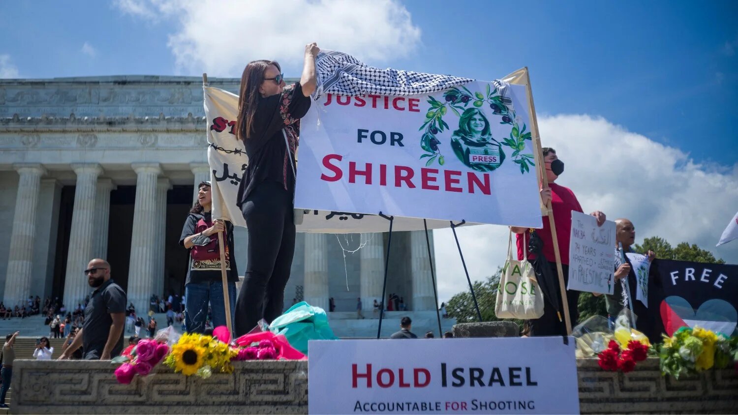 A woman drapes a keffiyeh on a banner calling for justice for Shireen Abu Akleh during a rally in Washington, DC on 15 May 2022.