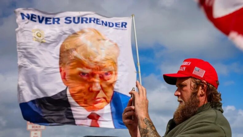 A person shows support for US president-elect Donald Trump near his Mar-a-Lago resort on 14 December 2024 (Eva Marie Uzcategui/Getty Images/AFP)