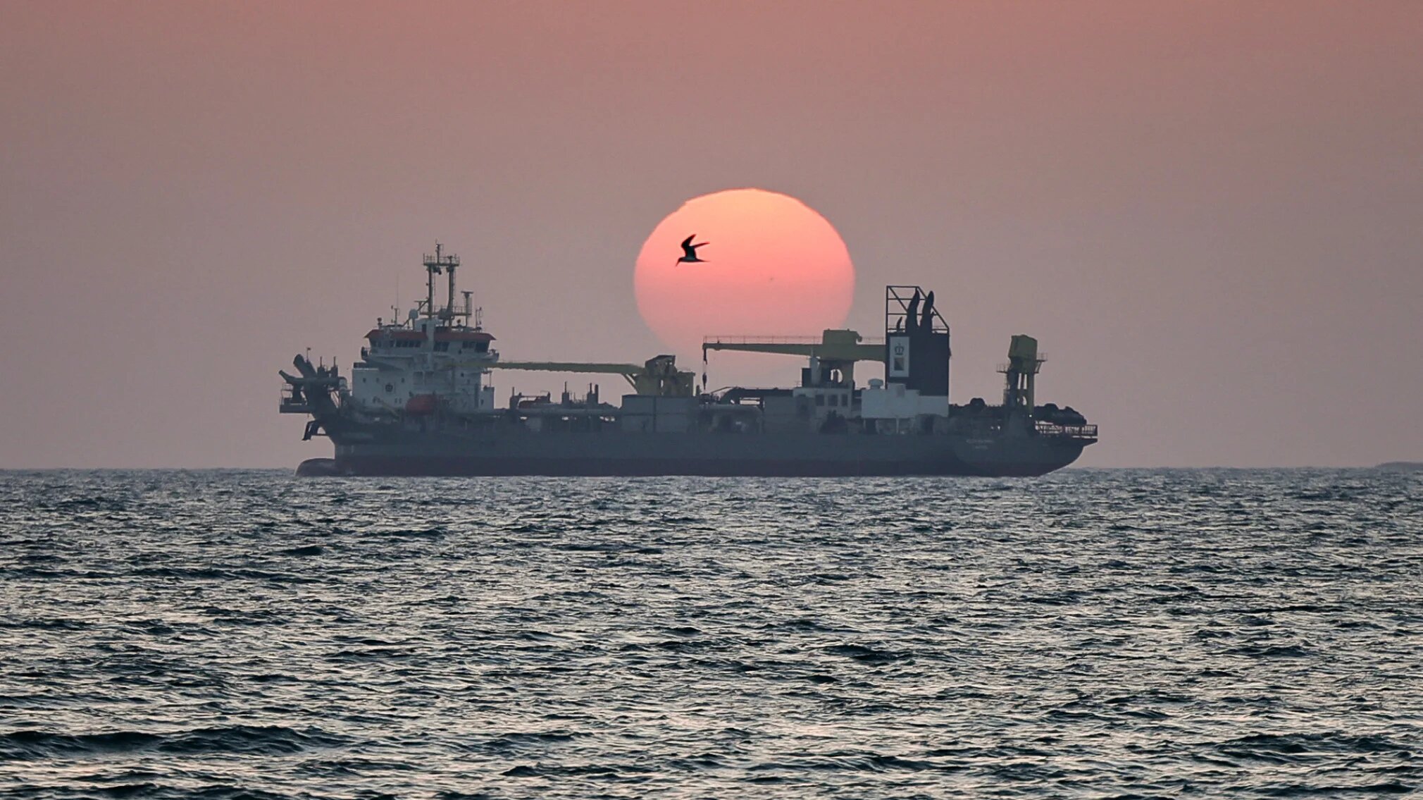 The sun sets over a vessel off the coast of Dubai on 2 June 2026 (AFP)