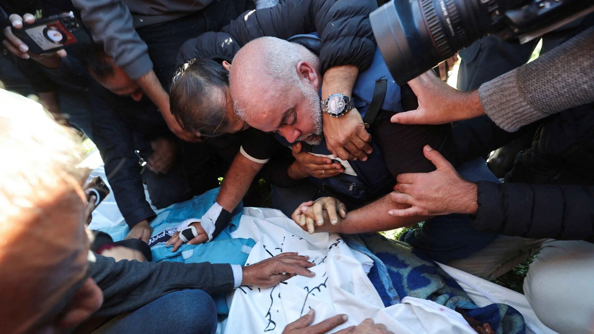 Al Jazeera journalist Wael Al-Dahdouh hugs his daughter and son as they attend the funeral of his son, Palestinian journalist Hamza Al-Dahdouh in Rafah, southern Gaza on 7 January 2024 (Mohammed Salem/Reuters)