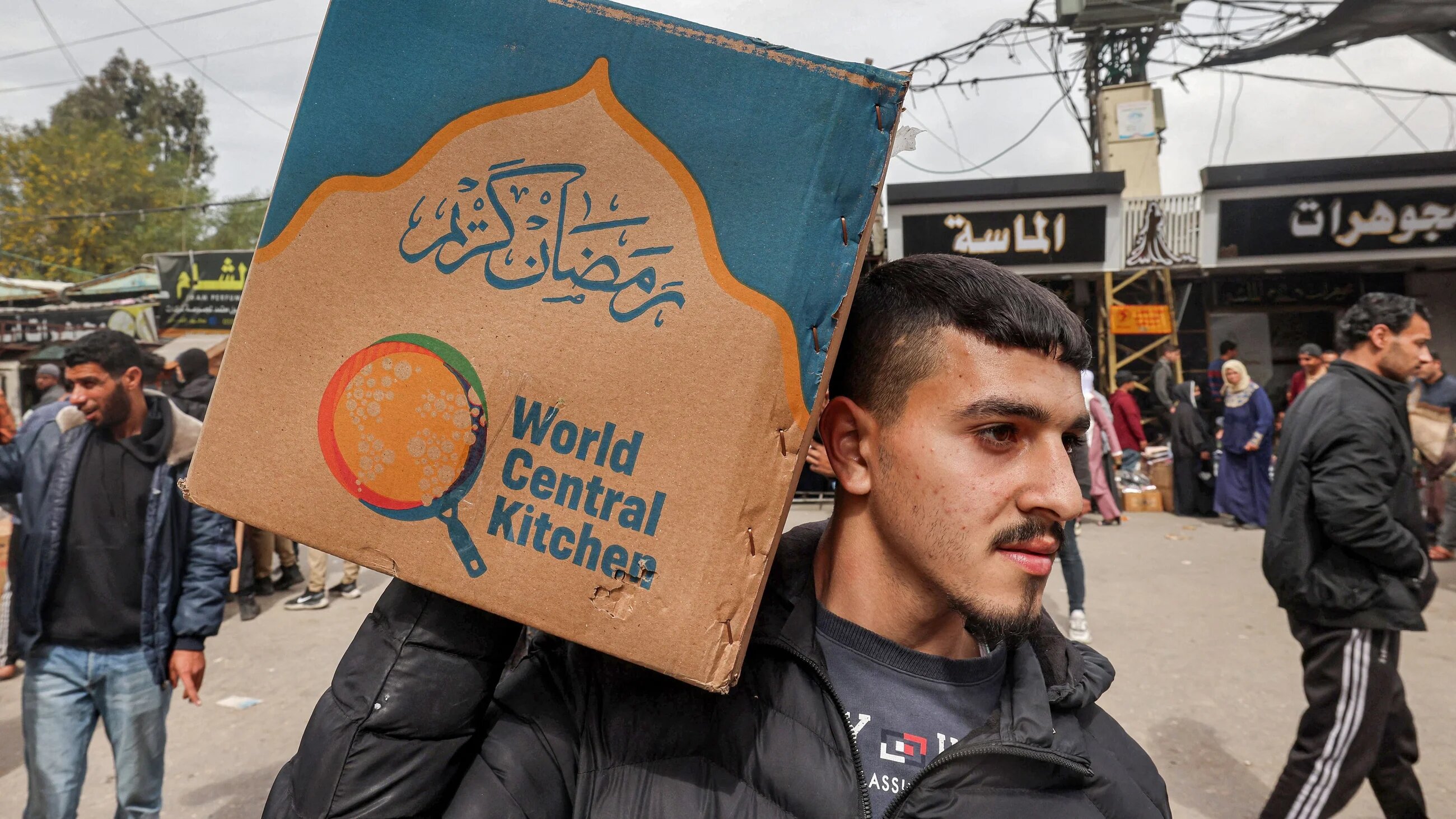 A man carries a box of food aid provided by the World Central Kitchen in Rafah, south Gaza, on 17 March, 2024 (AFP/Mohammed Abed)