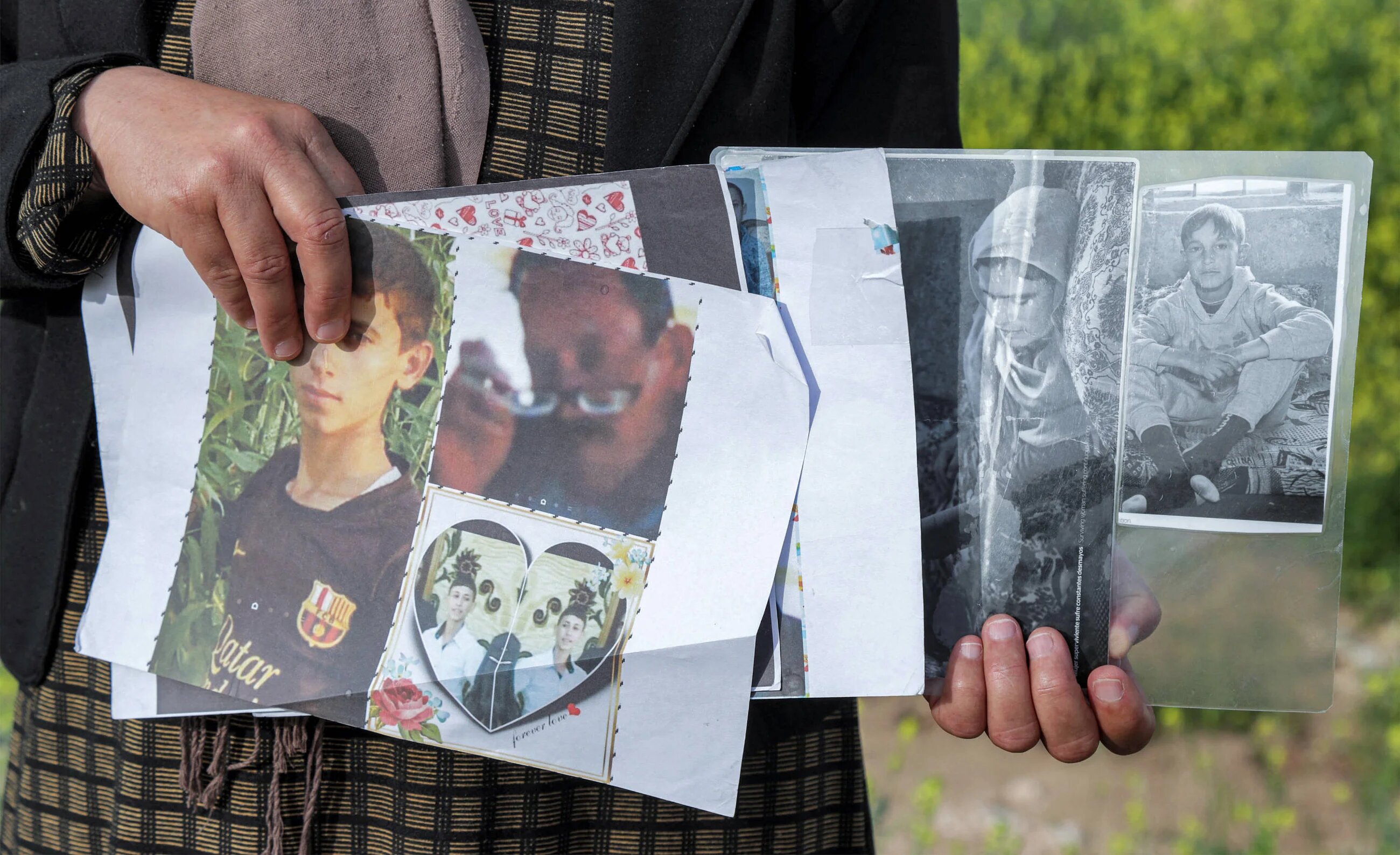A displaced Yazidi woman holds photos of family members kidnapped by the Islamic State group in the Sharya region, some 15 km near the northern Iraqi city of Dohuk, 19 April 2023 (Safin Hamid/AFP)