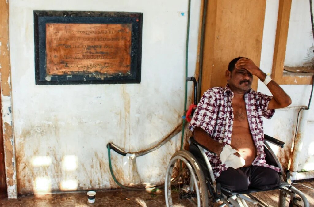 Un homme amputé est assis à côté d’une plaque commémorative datant l’année 1954, quand la reine Elizabeth II a posé la première pierre de à l'hôpital Al-Joumhouria dans la région de Khor Maksar de la ville d’Aden, dans le sud du Yémen (AFP/Saleh Obaidi)