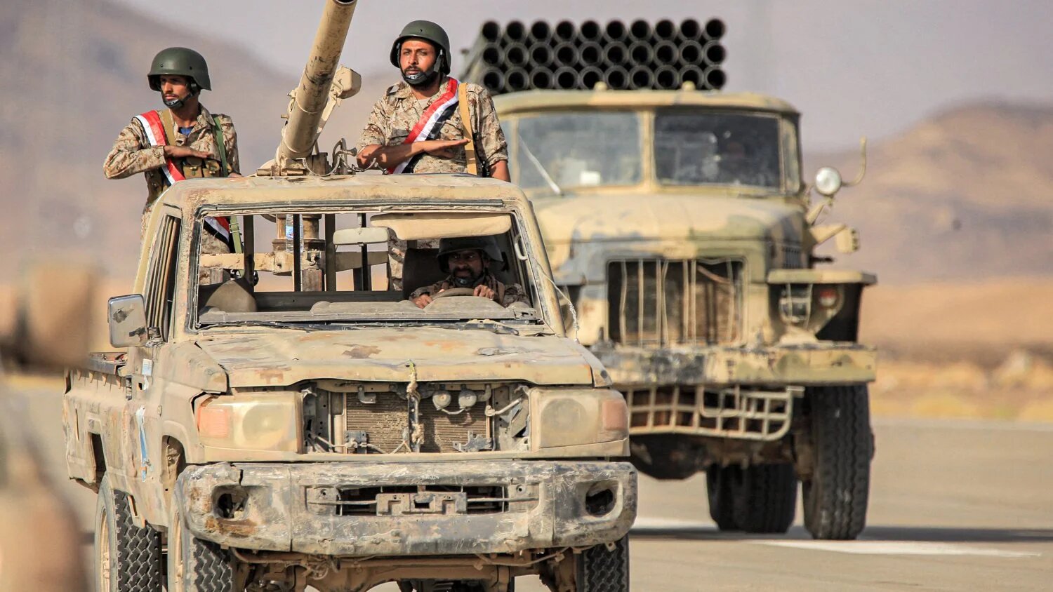 Soldiers ride in the back of a pickup truck armed with a turret during a military parade of the Saudi-backed Yemeni government in Marib on 16 June 2022.