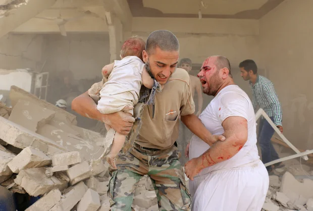 A Syrian man carries a wounded child following a barrel bomb attack on the Bab al-Nairab neighbourhood of the northern Syrian city of Aleppo on 25 August 2016 (AFP)