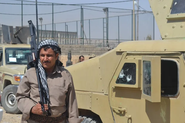 Peshmerga fighters stand next to damaged vehicles (MEE / Sheren Khalel) 