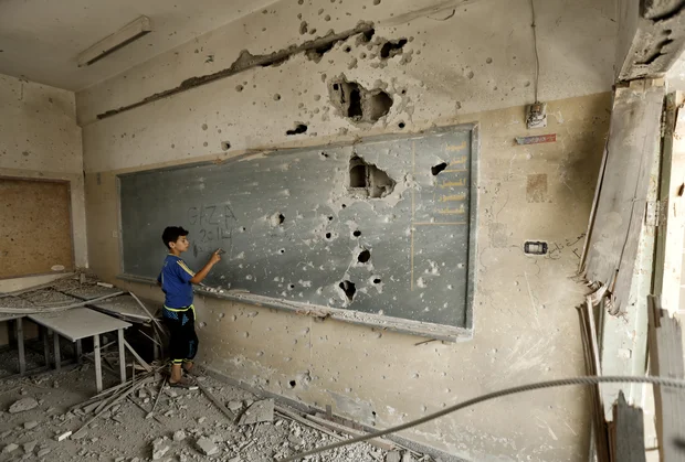 Boy inspects the damage to his school (AFP) 