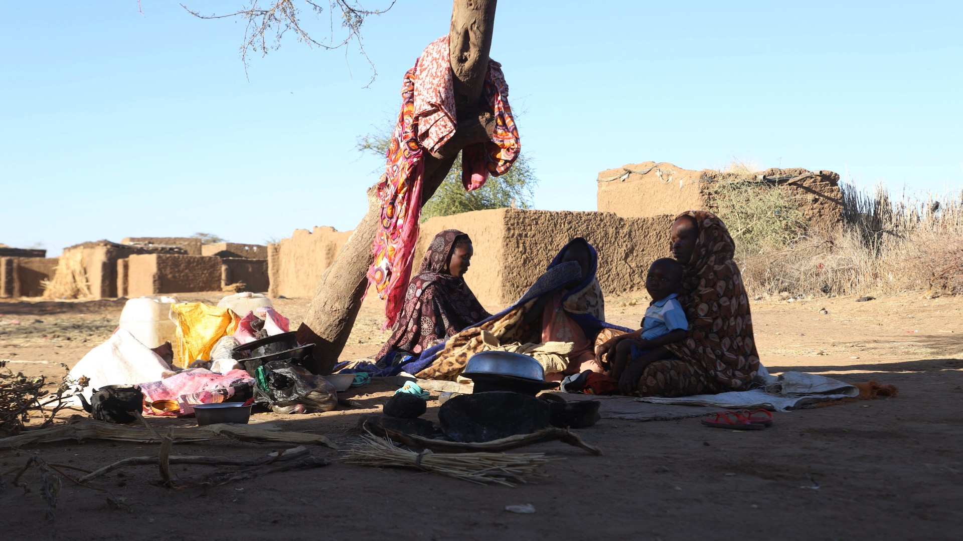 Sudanese displaced people who left El-Fasher after its fall, sit in the shade in Tawila at the Rwanda camp reception point on December 17, 2025