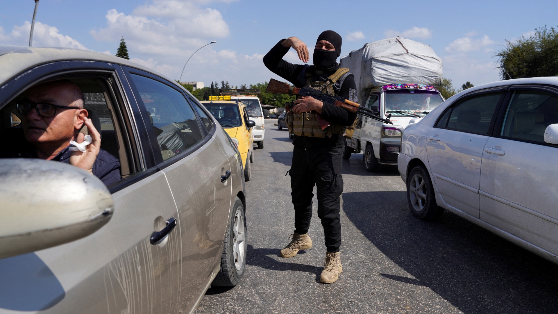 A member of the Syrian security forces gestures as he stands between cars in Latakia, Syria 10 March (Reuters/Karam al-Masri)