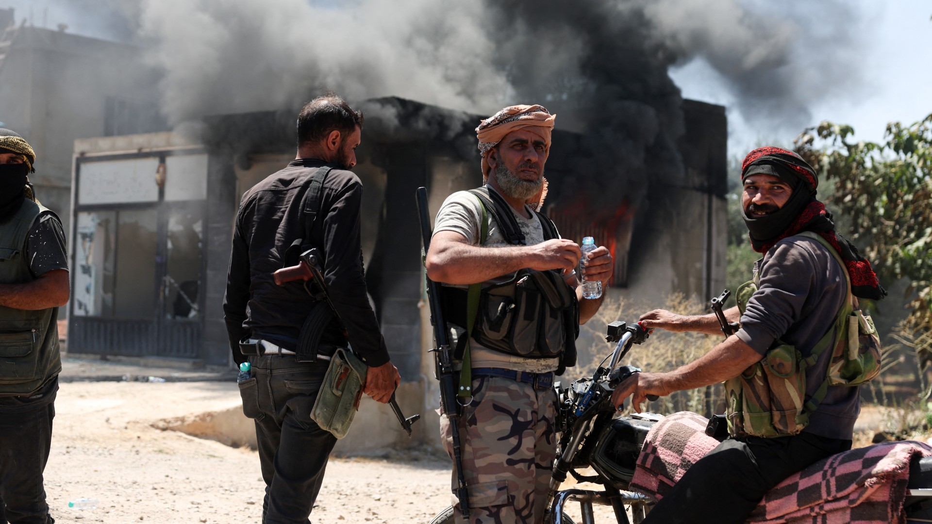 Heavy smoke rises from a burning building as fighters from Bedouin tribes gather in al-Mazraa village, in Syria's southern Sweida governorate on 18 July 2025 (Omar Haj Kadour/AFP)