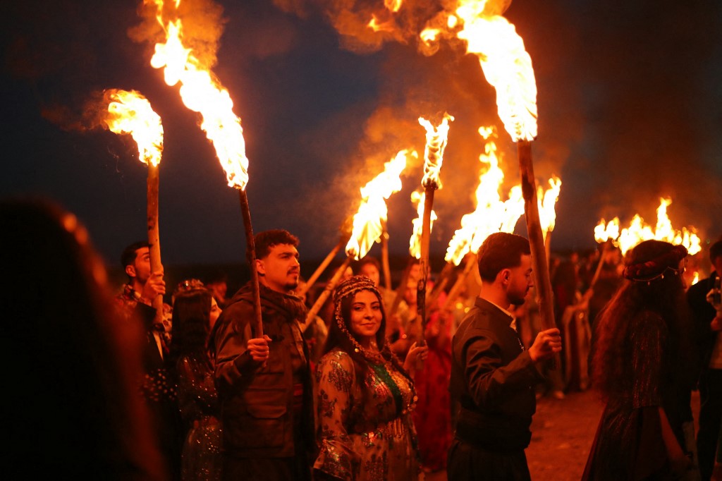 Syrian Kurds carry the flame to mark the Nowruz holiday, the Kurdish spring festival, in the village of Tel Mozan in the countryside of Qamishli, northeastern Syria, on March 18, 2026. Delil SOULEIMAN / AFP