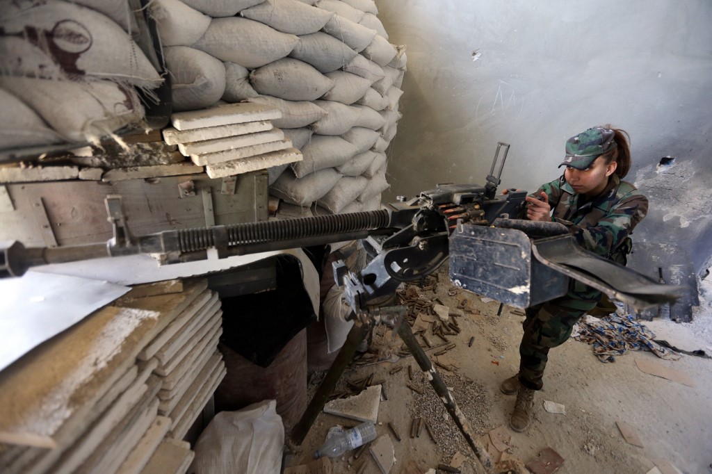A Syrian soldier from the Republican Guard fires a machine gun during clashes with rebels in eastern Damascus in 2015 (AFP)