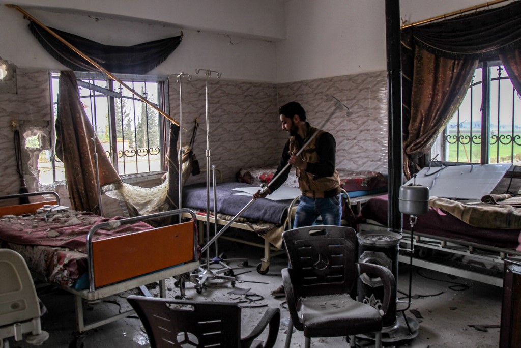 A Syrian man tries to clear rubble at a damaged hospital in Idlib province on 10 March (AFP)