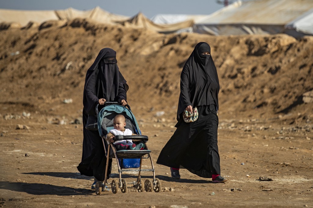Syrian women walk through a camp in northeastern Syria on 14 January (AFP)