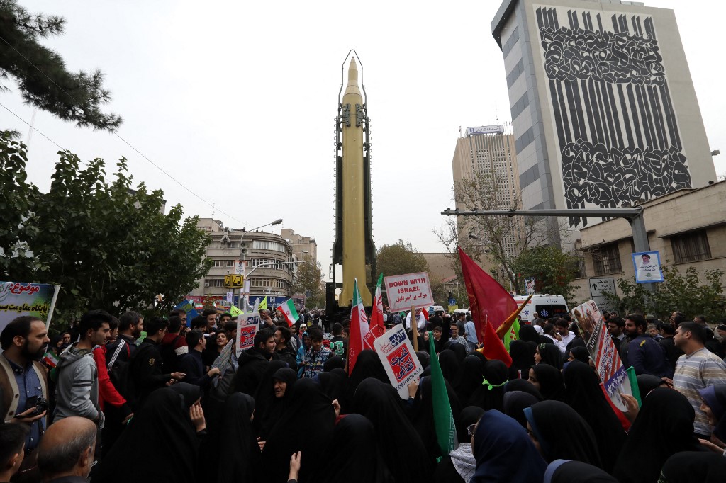 Iranians gather next to a replica of a Ghadr medium-range ballistic missile during a demonstration outside the former US embassy in Tehran in 2017 (AFP)